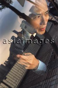 Asia Images Group - Male executive with cellular phone, skyline reflected in car window