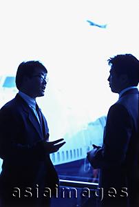Asia Images Group - Two male executives talking in airport lounge