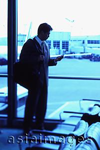 Asia Images Group - Male executive holding cellular phone in airport lounge