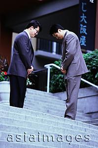 Asia Images Group - Two male executives bowing on stairway