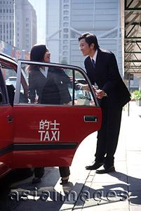 Asia Images Group - Female executive getting into taxi, male executive holding door