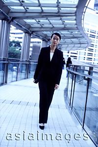 Asia Images Group - Female executive walking along aisle of building
