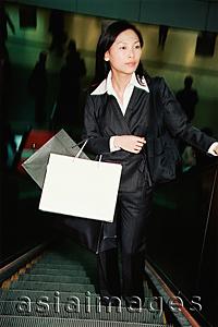 Asia Images Group - Woman on escalator, carrying shopping bags