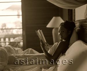 Asia Images Group - Woman in bed holding book