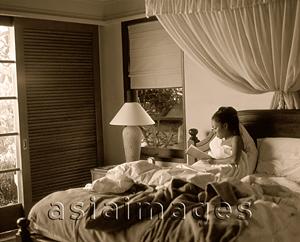 Asia Images Group - Woman in bed holding book