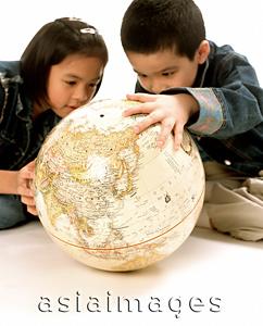 Asia Images Group - Young girl and boy looking at globe.