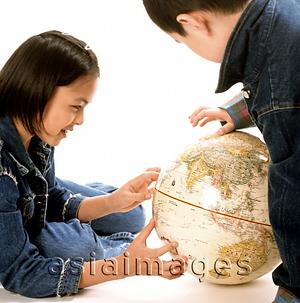Asia Images Group - Young girl and boy looking at globe, Asia prominent .
