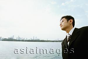 Asia Images Group - Male executive looking across water, blue sky in background