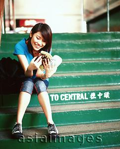 Asia Images Group - Young woman sitting on steps, reading book.