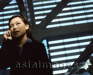 Asia Images Group - Executive woman using cellular phone indoors.