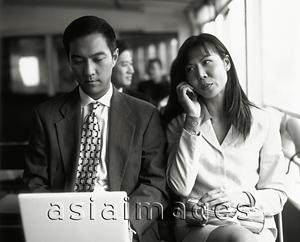 Asia Images Group - Male executive on laptop, female on cellular phone.