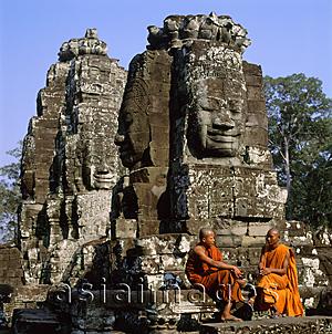 Asia Images Group - Cambodia, Angkor Thom, monks sitting at foot of Face towers, the Bayon