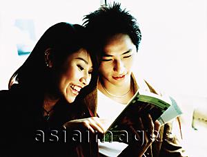 Asia Images Group - Young couple looking at book together.