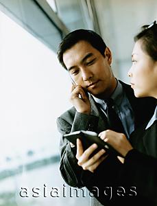 Asia Images Group - Executives using PDA and cellular phone.