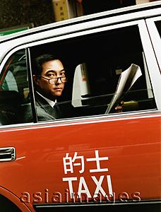 Asia Images Group - Executive wearing glasses holding newspaper in taxi.
