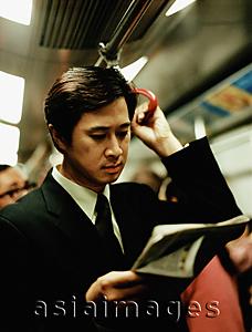 Asia Images Group - Executive in train reading newspaper.