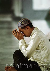 Asia Images Group - Malaysia, Kuala Lumpur, Malay man holds a small Koran and prays.