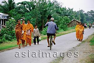 Asia Images Group - Vietnam, Mekong Delta region, Bac Lieu, Cyclist rides past Buddhist monks on road.