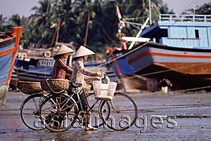 Asia Images Group - Vietnam, Women on bicycles wait for fishing boats to dock