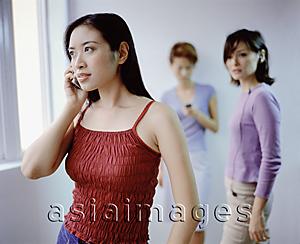 Asia Images Group - Young women using cellular phones.