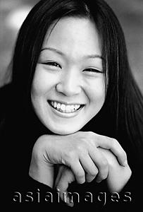 Asia Images Group - Young woman resting chin on hands, smiling.