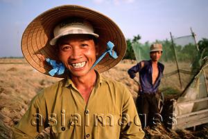 Asia Images Group - Vietnam, Mekong Delta, Smiling farm workers threshing rice. (grainy)