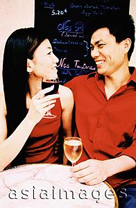 Asia Images Group - Young couple sitting at outdoor cafe holding wine glasses, smiling. (high-grained)