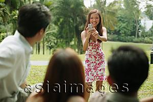 Asia Images Group - Young woman taking a picture of her friends