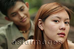Asia Images Group - Young woman looking at camera, young man in the background