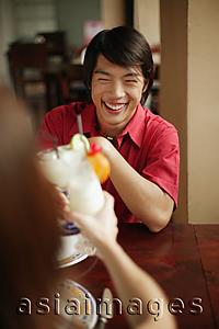 Asia Images Group - Young man and woman toasting with drinks