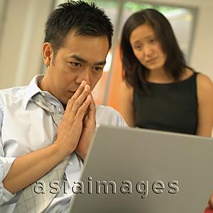 Asia Images Group - Man using laptop, woman watching him
