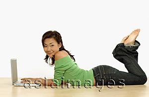 Asia Images Group - Young woman using laptop, lying on floor