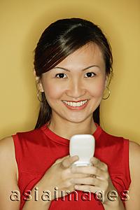 Asia Images Group - Young woman wearing a red top, holding a mobile phone