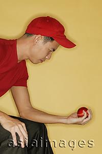 Asia Images Group - Young man sitting down and holding a ball in his hand