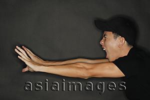 Asia Images Group - Young man reaching forward, stretching, mouth open