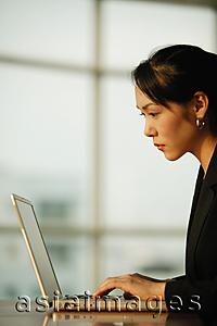 Asia Images Group - Young woman sitting at desk, using laptop