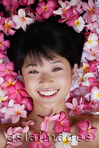 Asia Images Group - Young woman lying down amidst flowers, looking at camera