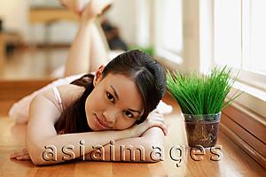 Asia Images Group - Young woman, lying down, head in arms, looking at camera