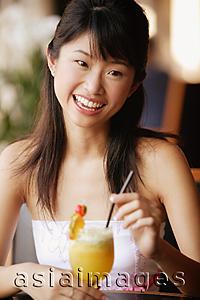 Asia Images Group - Young woman holding a drink, looking at camera