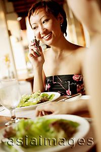 Asia Images Group - Young woman at restaurant, on the phone