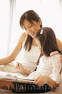 Asia Images Group - Mother and daughter, sitting side by side, looking at book