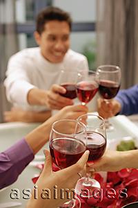 Asia Images Group - Friends toasting with wine glasses across dinner table