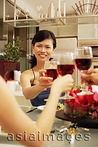 Asia Images Group - Friends toasting wine glasses across dinner table
