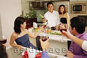 Asia Images Group - Group of friends having a dinner party at home, some raising wine glass