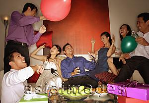 Asia Images Group - Group of friends having a party at home, holding balloons