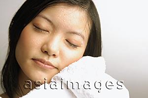 Asia Images Group - Young woman wiping her face with towel, eyes closed