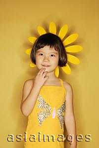 Asia Images Group - Young girl standing against yellow background, hand on chin