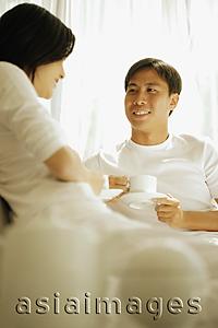 Asia Images Group - Couple having coffee, sitting on sofa.