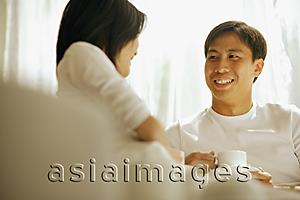 Asia Images Group - Couple having coffee, sitting on sofa.