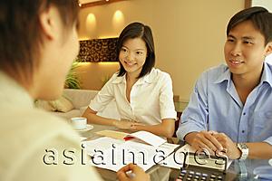 Asia Images Group - Three people sitting at table, calculator and papers infront of them